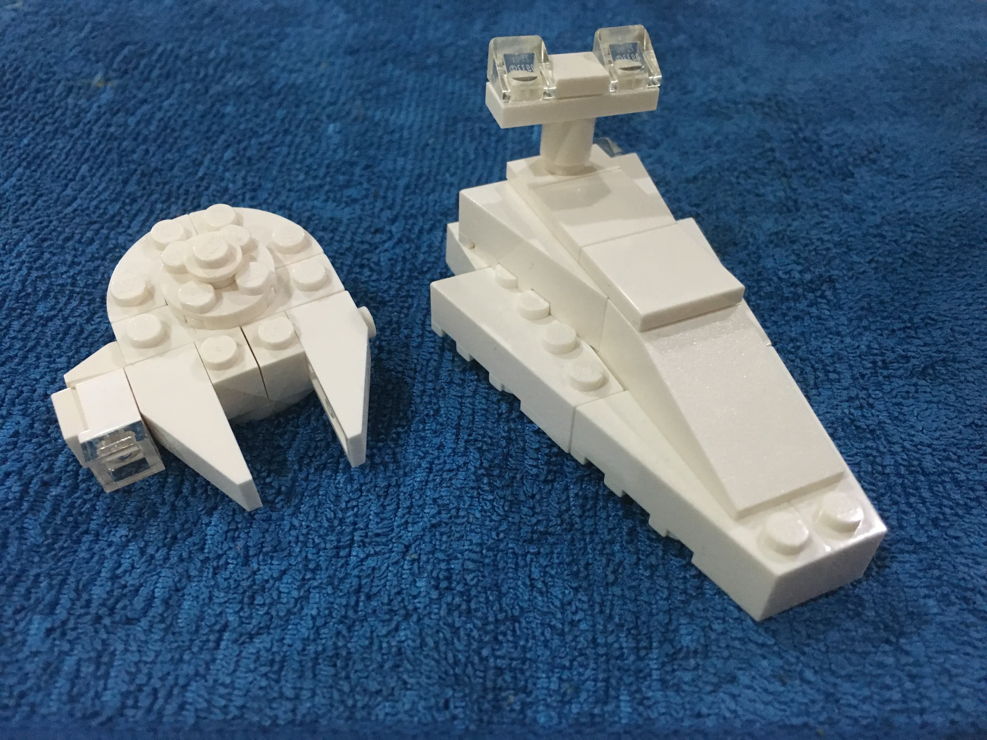 Two white LEGO vehicle forms on a blue fabric background.