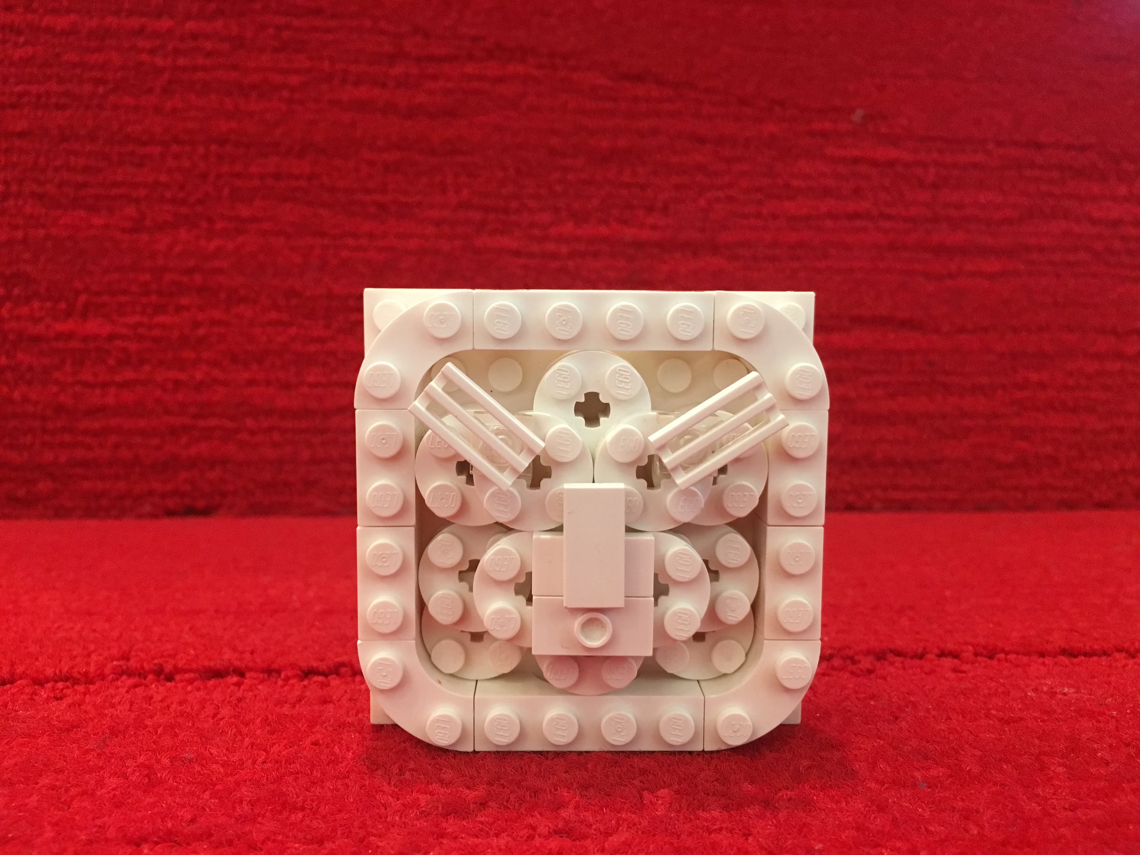 White LEGO architectural detail against a red fabric backdrop.