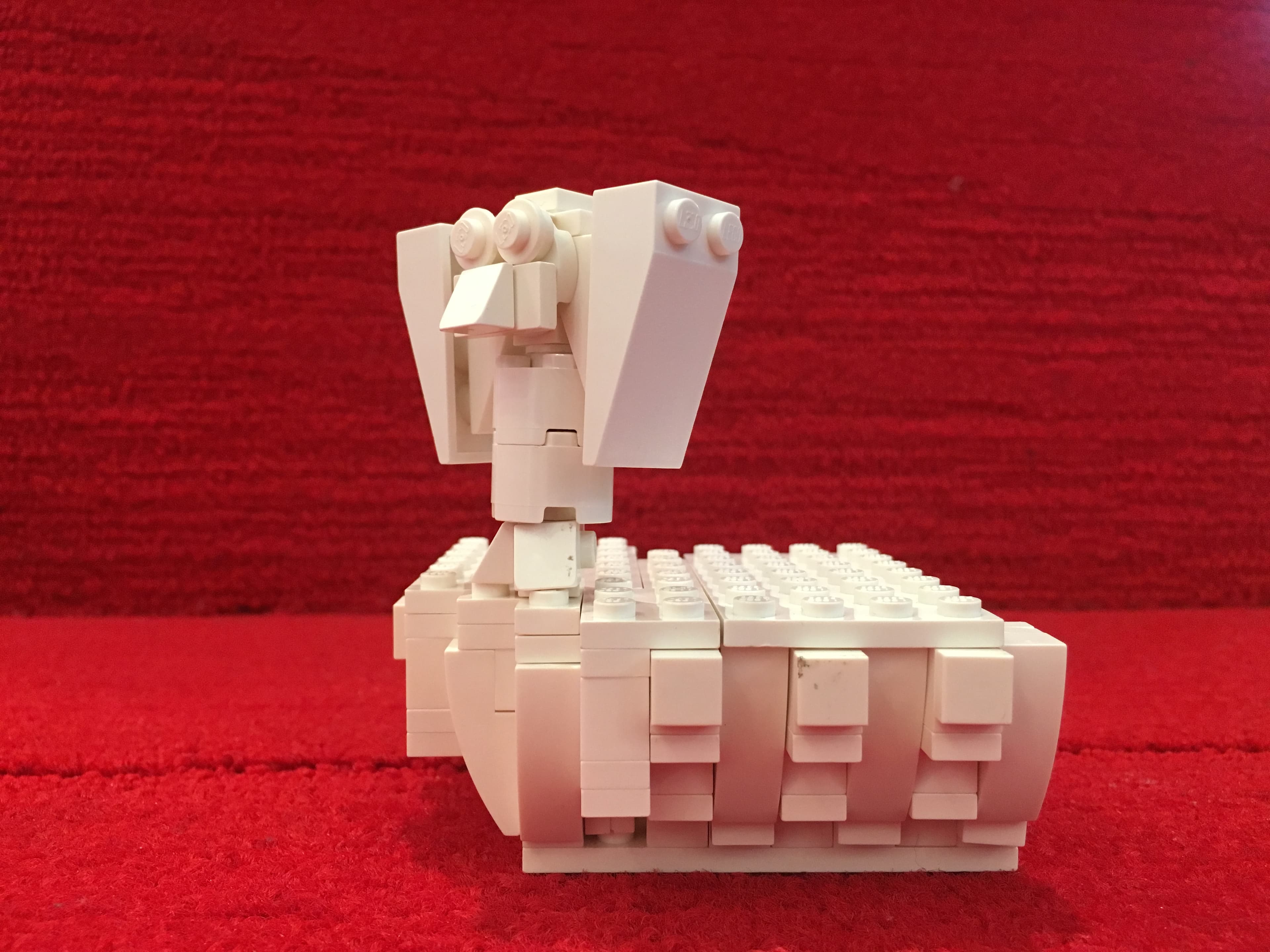 White LEGO architectural model against a red fabric backdrop.