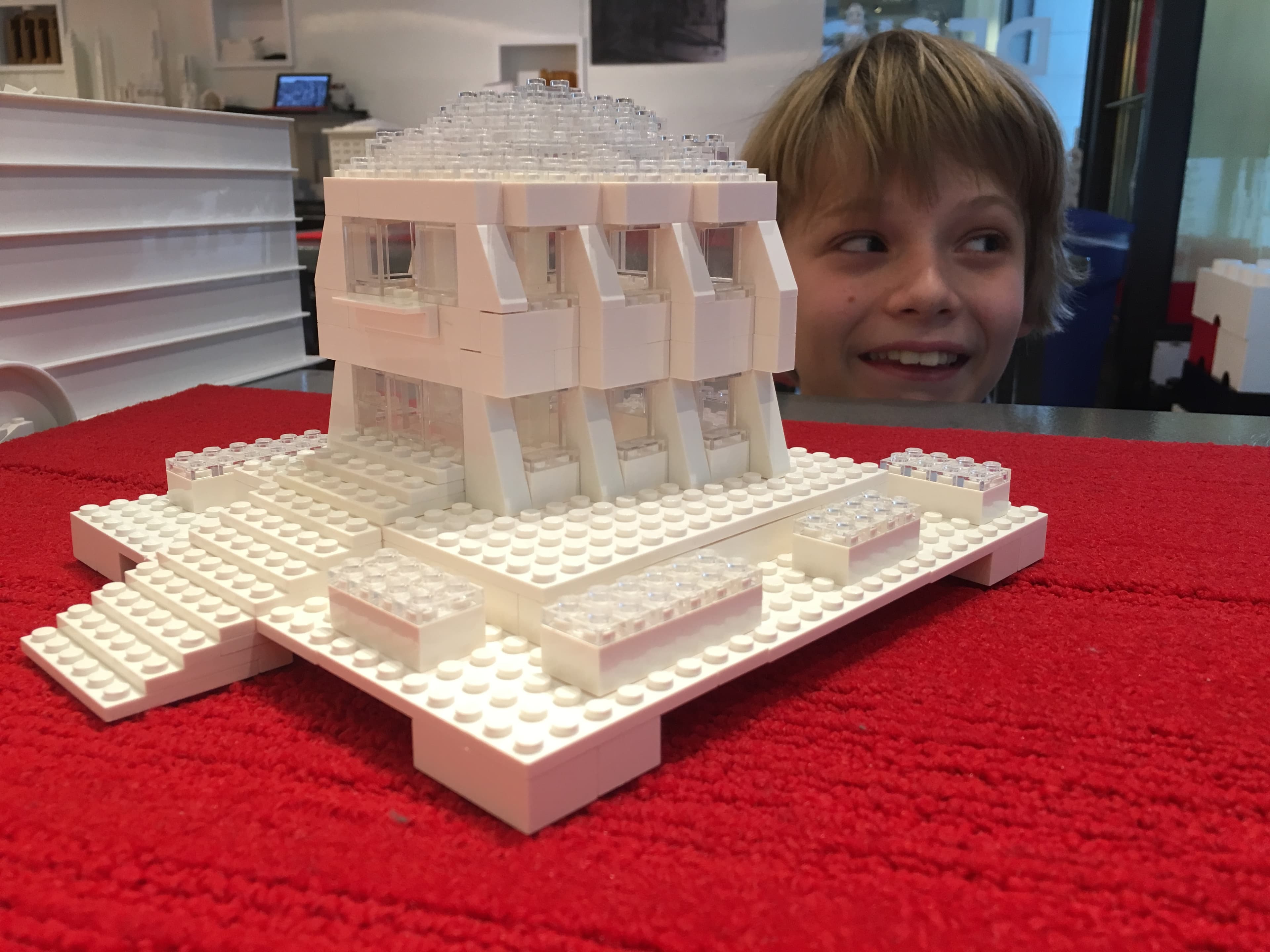 White LEGO architectural model with Alex smiling behind it.