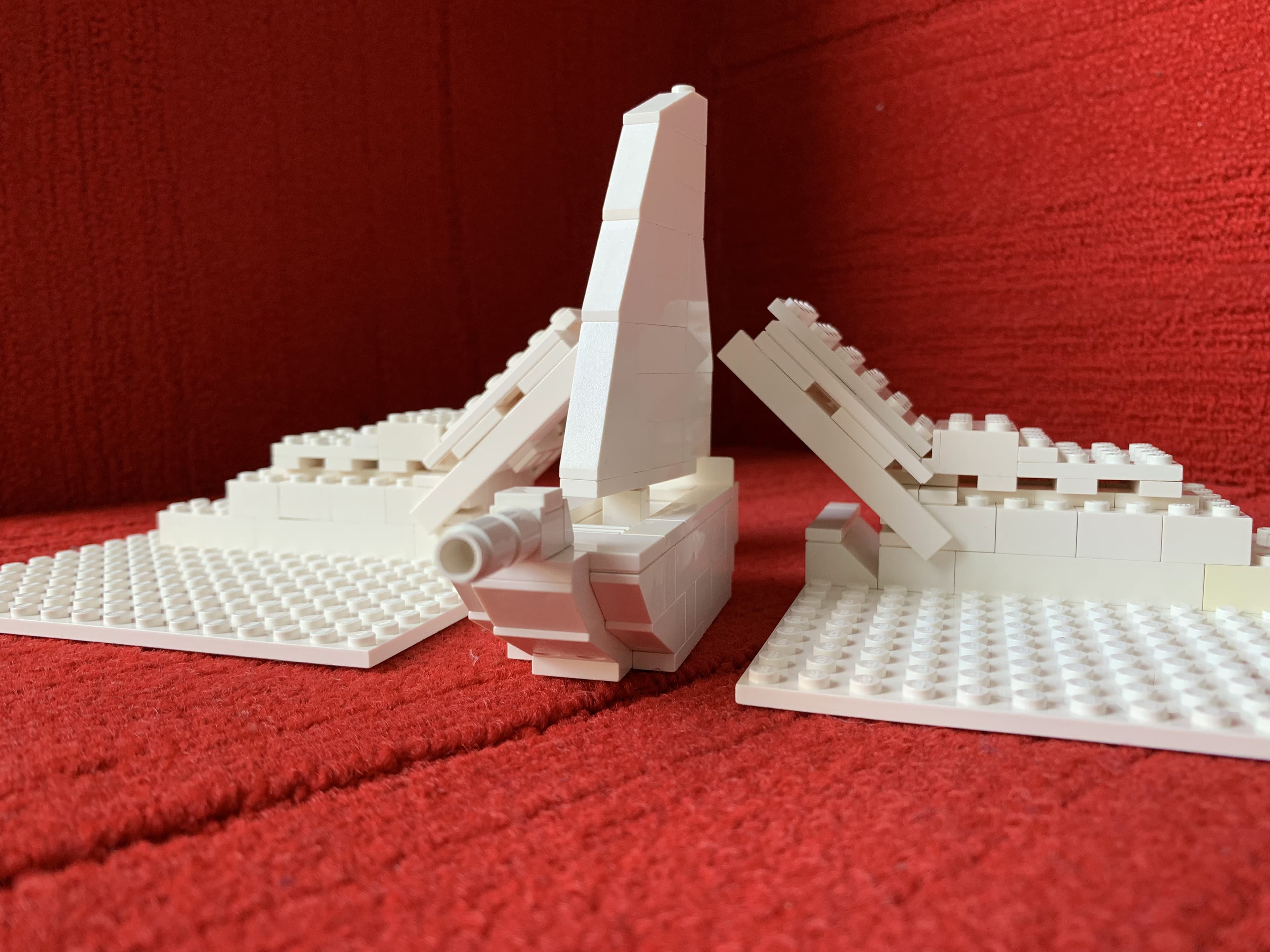 White LEGO architectural model on a red fabric backdrop.