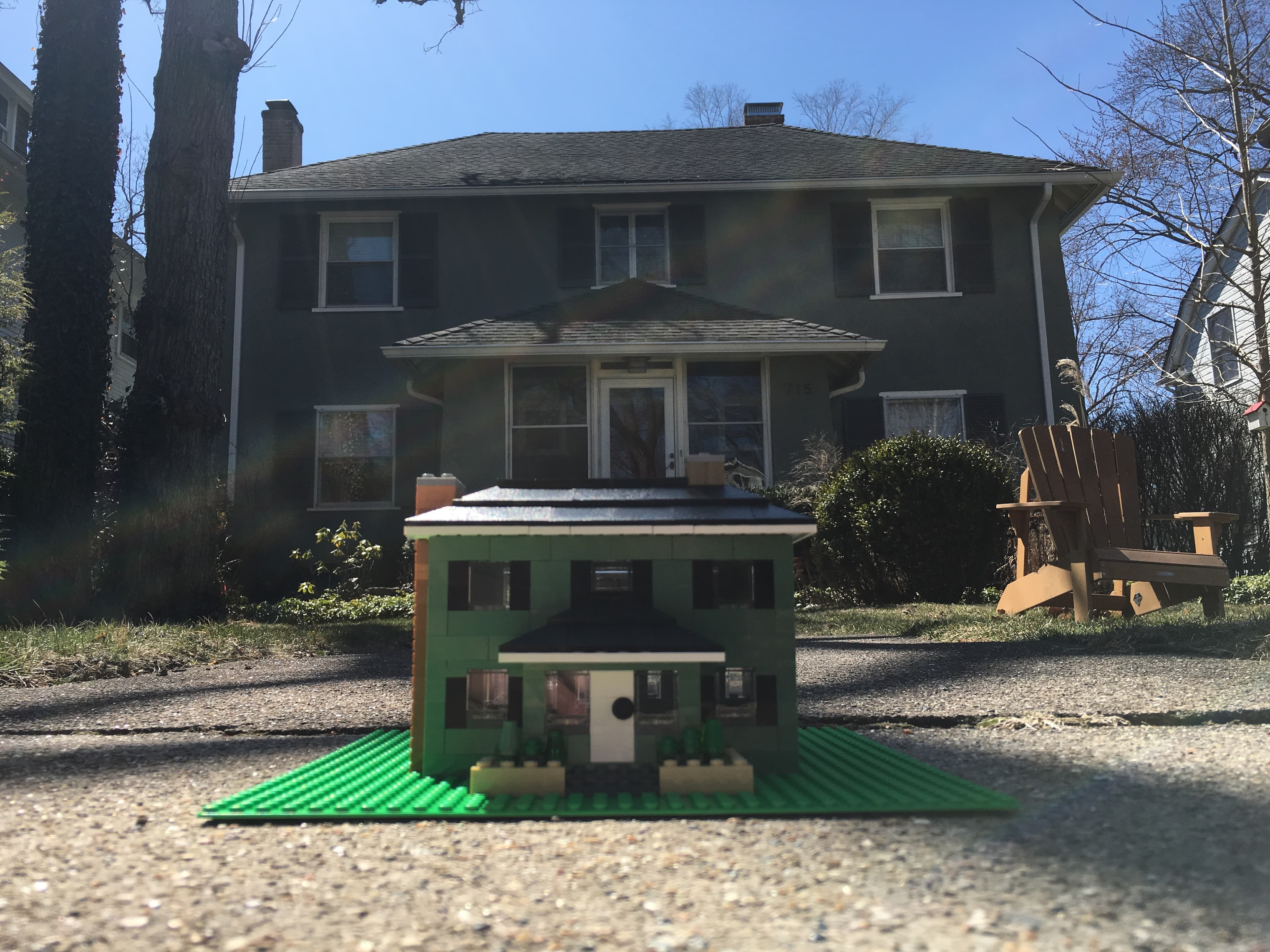 Green LEGO house model photographed in front of a full-size house.