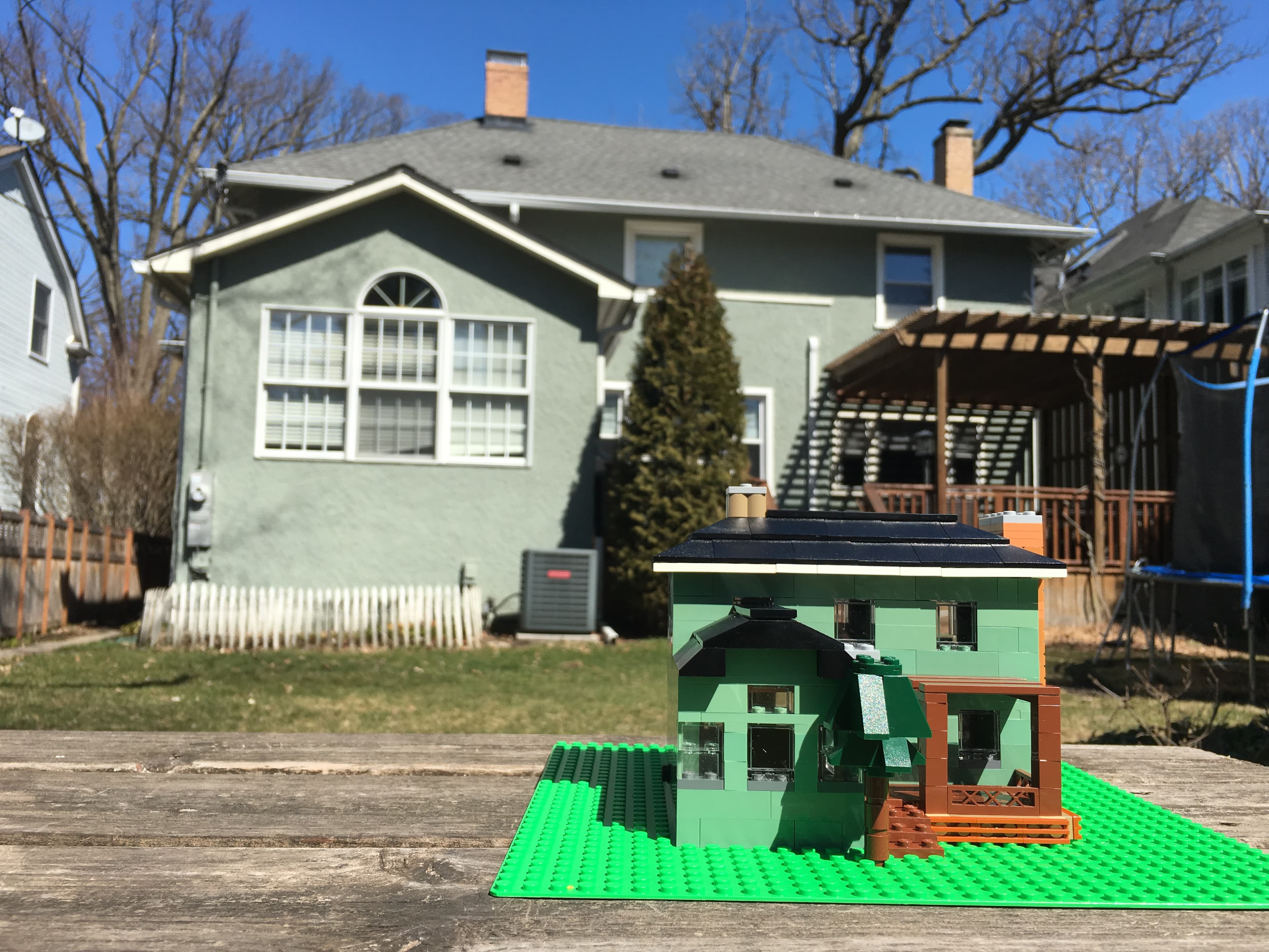 Green LEGO house model photographed in a backyard.